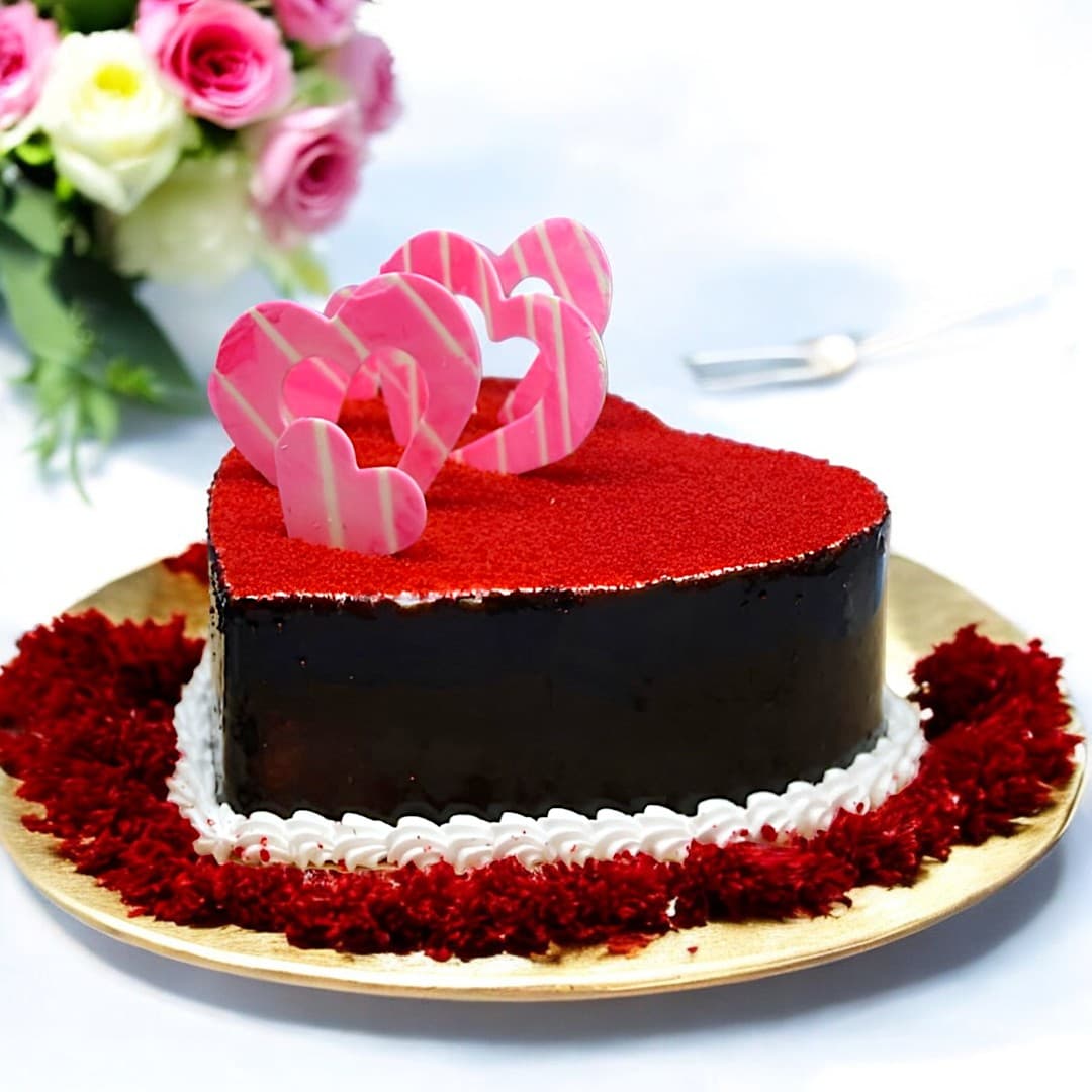 Red velvet heart shape cake with red velvet crumbs and pink heart chocolate decorations