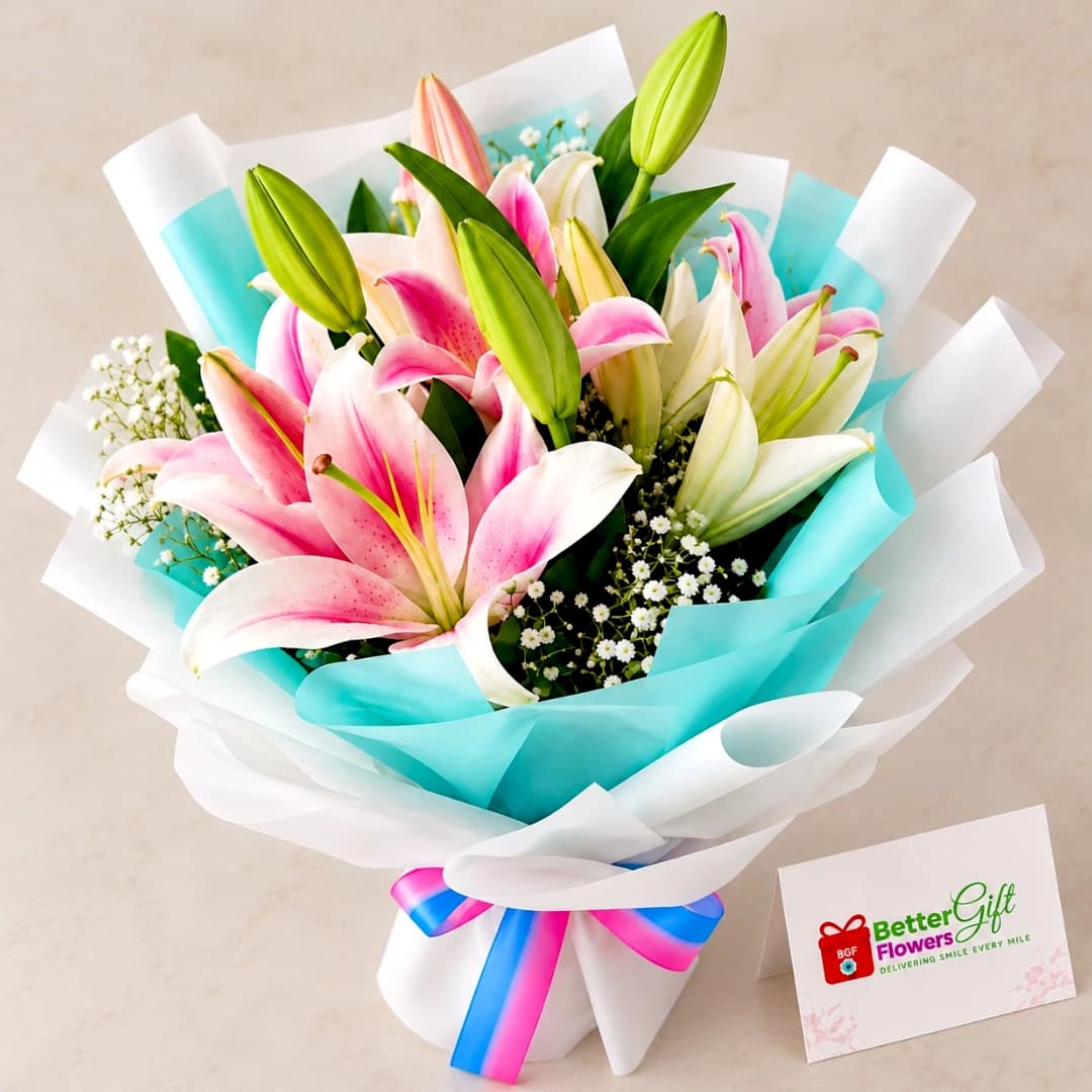 Close-up view of pink and white lilies with green buds and baby’s breath in an elegant wrapped bouquet.