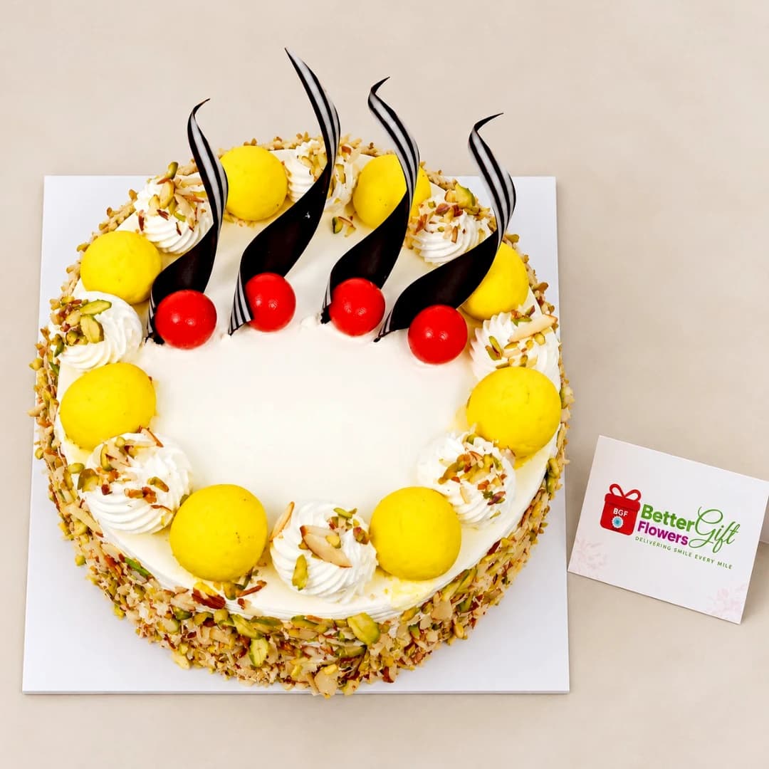 Top view of Kesar Rasmalai Almond Cake with creamy white frosting, rasmalai pieces and chocolate garnishes.