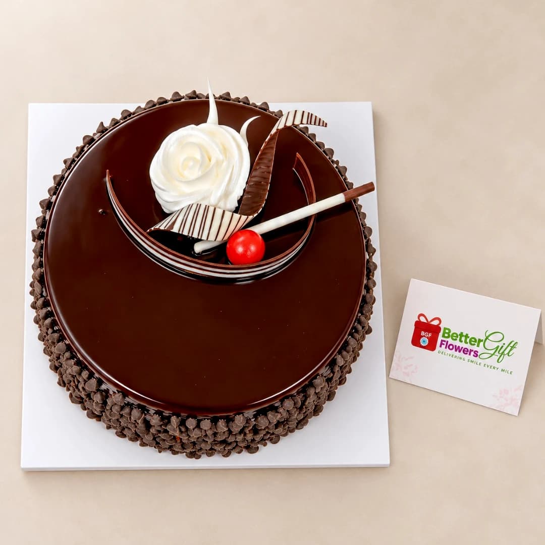 Top view of Choco Chip Cake decorated with chocolate curls, a cream rose and a red cherry.