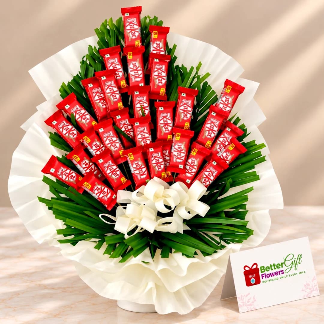 KitKat chocolate bouquet arranged with green decorative foliage, white wrapping and an elegant white bow.