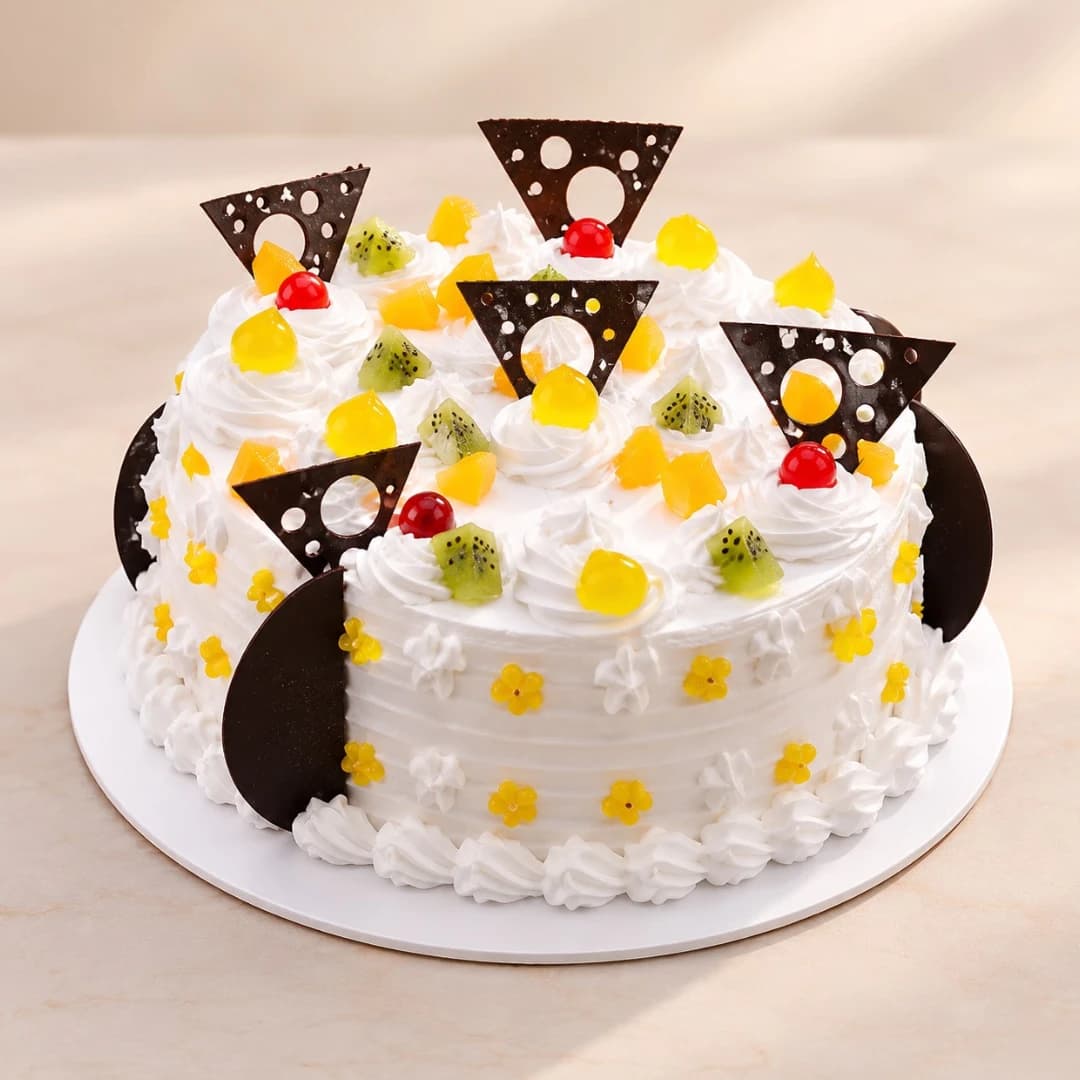 Mixed fruit cream cake with kiwi, pineapple, cherries and chocolate decorations
