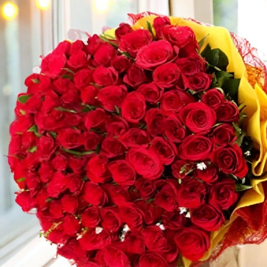 Close-up view of BetterGiftFlowers Addicted bouquet featuring 100 red roses wrapped in yellow and red paper.