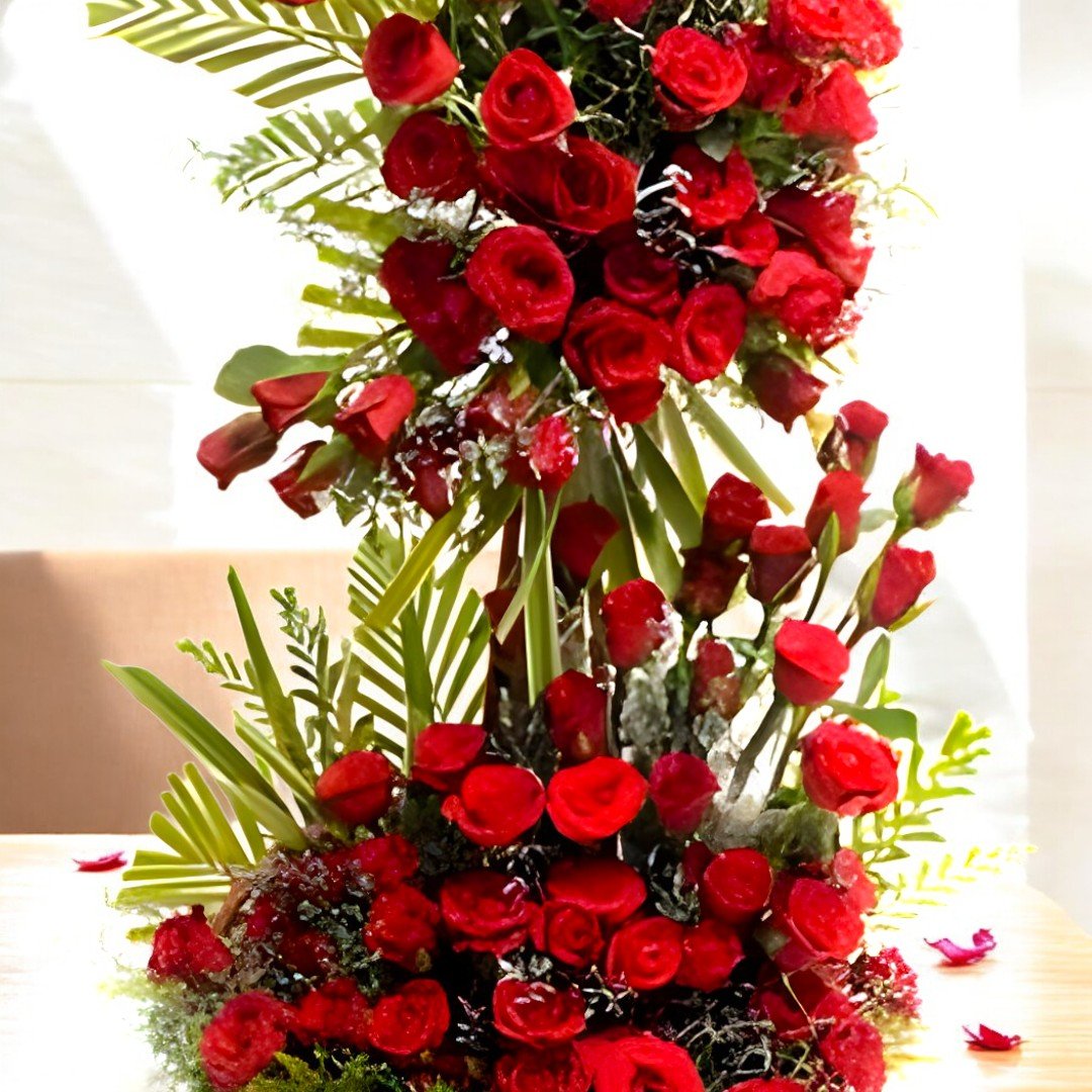 Close-up of BetterGiftFlowers 75 red roses Love Devotion arrangement with lush green leaves