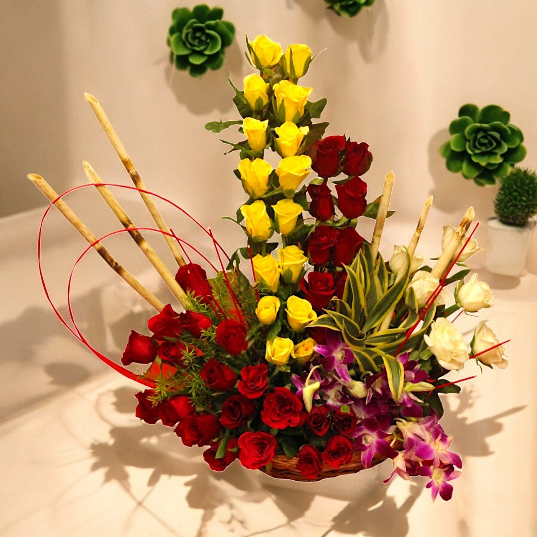 Vibrant floral arrangement with yellow, red, and white roses, and orchids by BetterGiftFlowers.