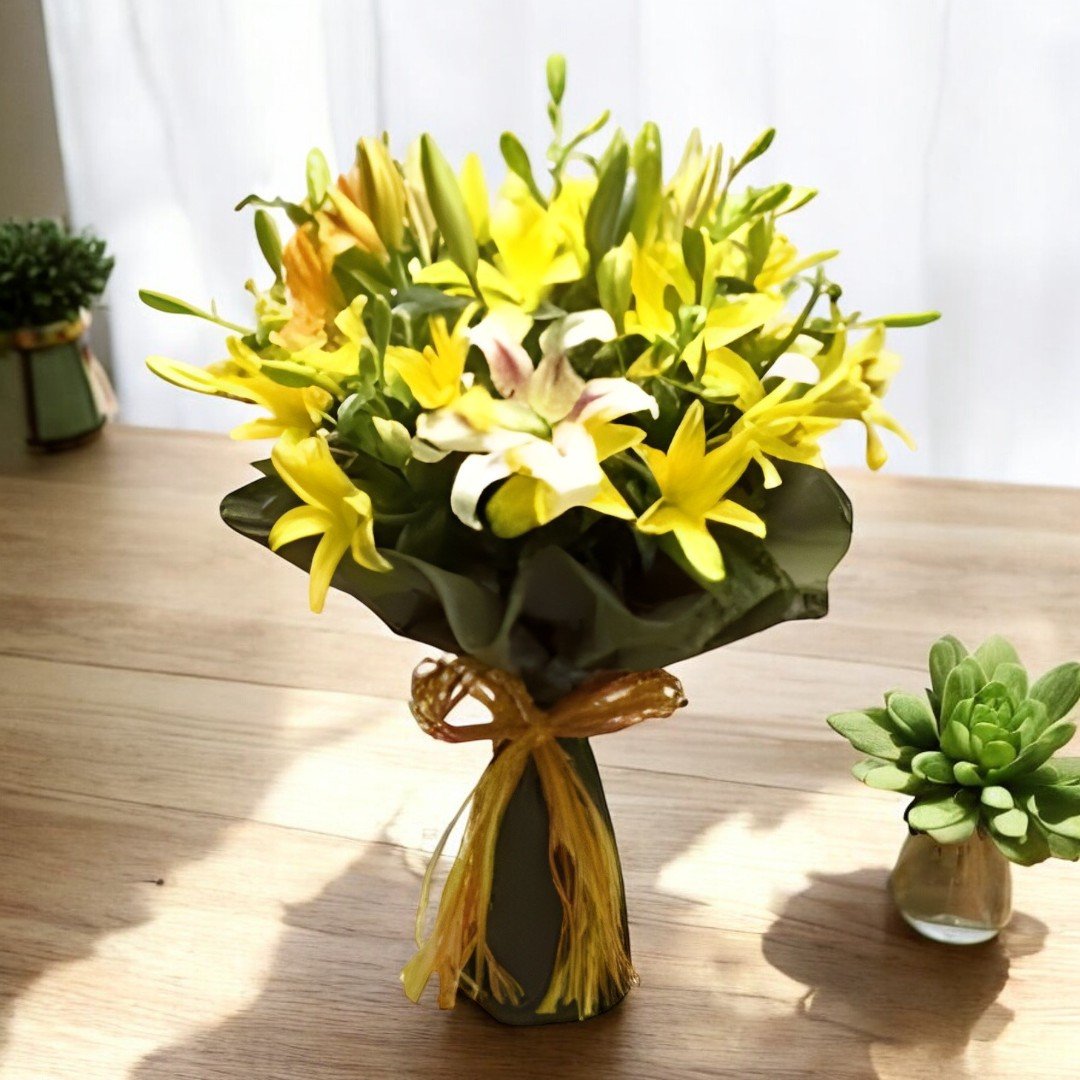 A beautiful bouquet of 12 Asiatic lilies in yellow, arranged in a clear vase by BetterGiftFlowers.