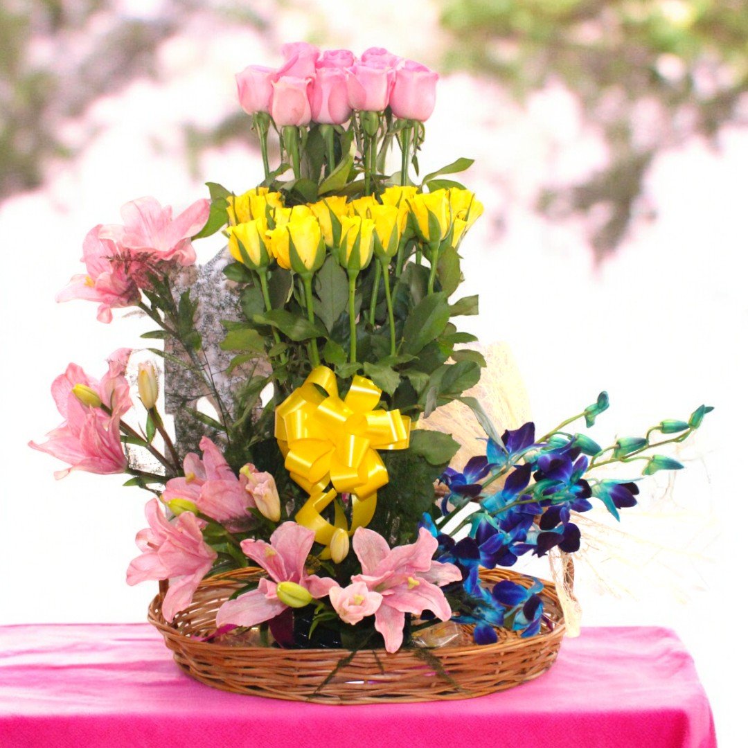 An Astounding Arrangement basket of pink roses, yellow roses, orchids, and lilies by BetterGiftFlowers.