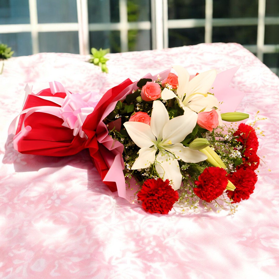 A beautiful "Bloom & Blossoms" bouquet featuring carnations, lilies, and roses by BetterGiftFlowers on a pink background.