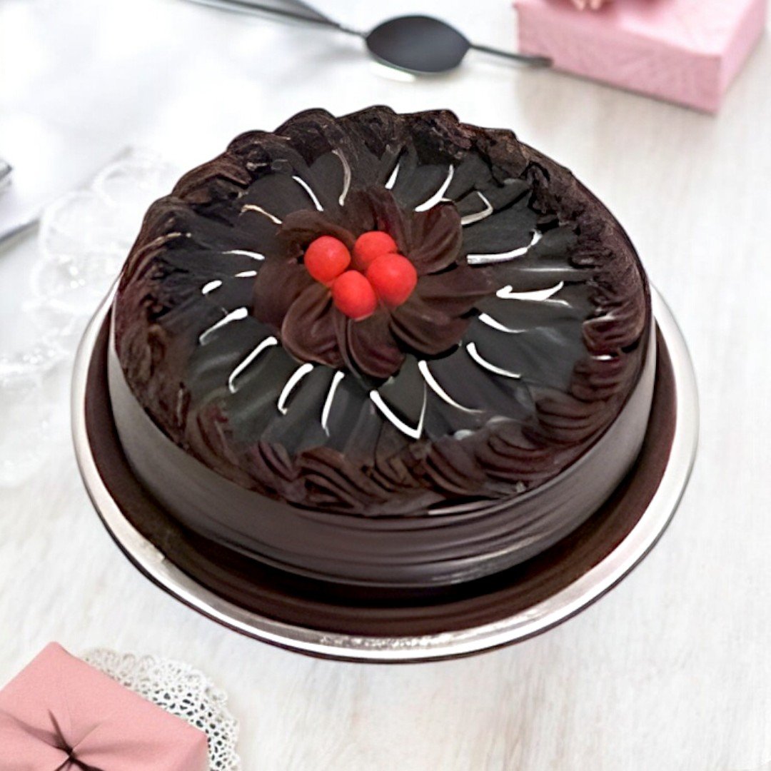 A delicious half kg chocolate truffle cake from Better Gift Flowers, topped with cherries and intricate icing details.