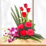 Flair floral arrangement featuring red roses, pink carnations, and orchids in a beautiful basket from Better Gift Flowers.