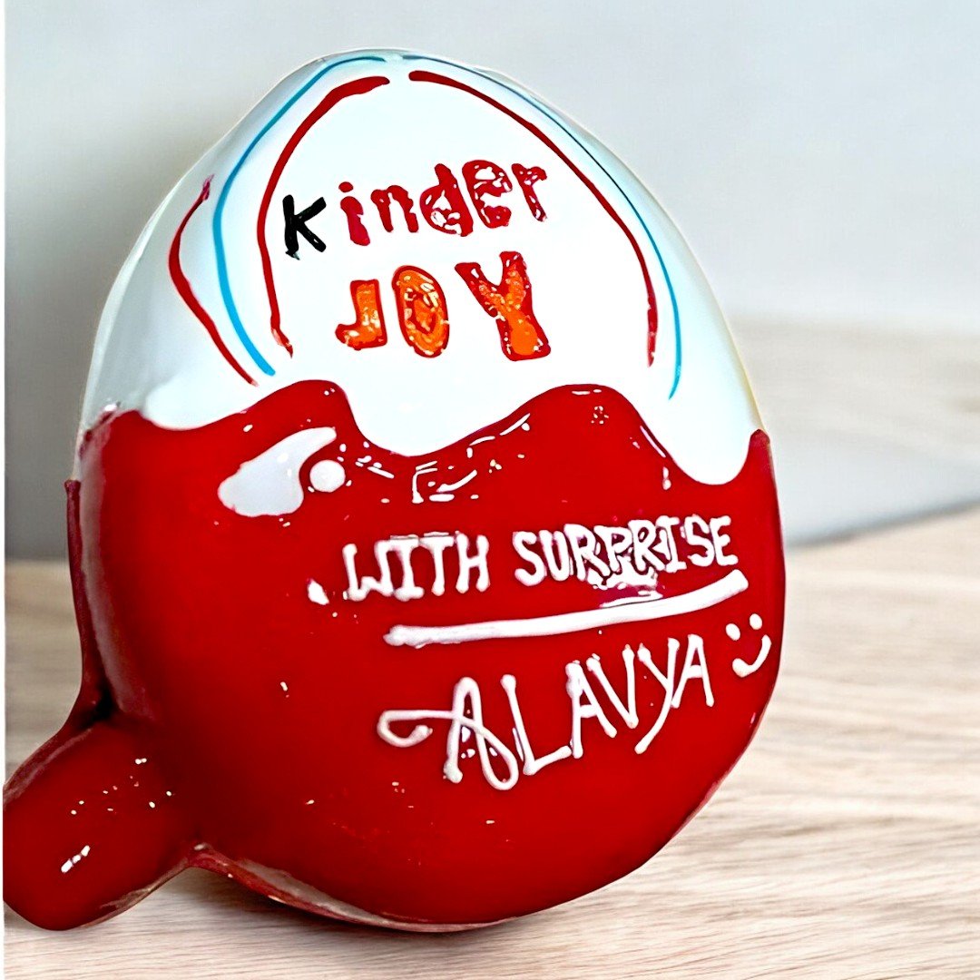 Kinder Joy cake with personalized name Alavya by BetterGiftFlowers, shaped like the iconic chocolate egg.