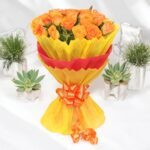 A stunning bouquet of 20 fresh orange roses wrapped in yellow and red paper, available at BetterGiftFlowers™.