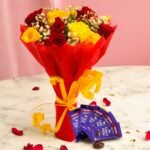 A vibrant bouquet of red and yellow roses with Dairy Milk chocolates, by BetterGiftFlowers.