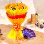 BetterGiftFlowers orange rose bouquet with Dairy Milk chocolates arranged on a wooden table.