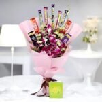 Orchids and Chocolates bouquet by BetterGiftFlowers - A bouquet of fresh orchids paired with chocolates wrapped in pink paper.