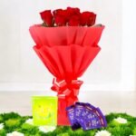 A vibrant bouquet of red roses with Dairy Milk chocolates by BetterGiftFlowers, placed on green grass for a stunning visual effect.