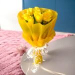 Yellow Rose Bouquet wrapped in yellow tissue paper by BetterGiftFlowers placed on a white surface.