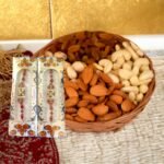 BetterGiftFlowers Rakhi and Dry Fruit Combo featuring two red designer rakhis and a basket of mixed dry fruits.