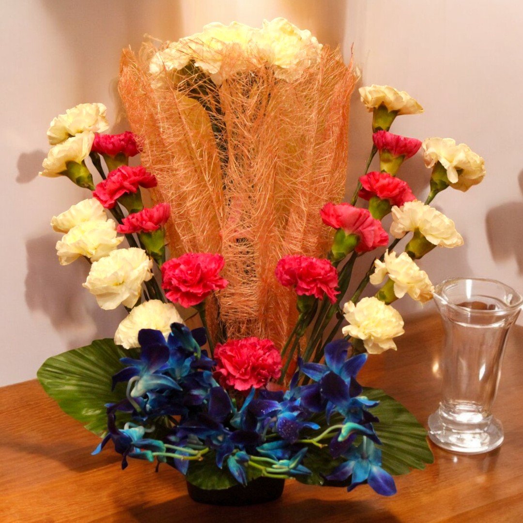 A stunning Carnations and Orchids bouquet by BetterGiftFlowers with vivid red, white, and blue flowers arranged in a unique style.