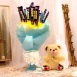 BetterGiftFlowers Perk Bouquet with Teddy, featuring blue and yellow wrapping with a cute teddy bear by the side.