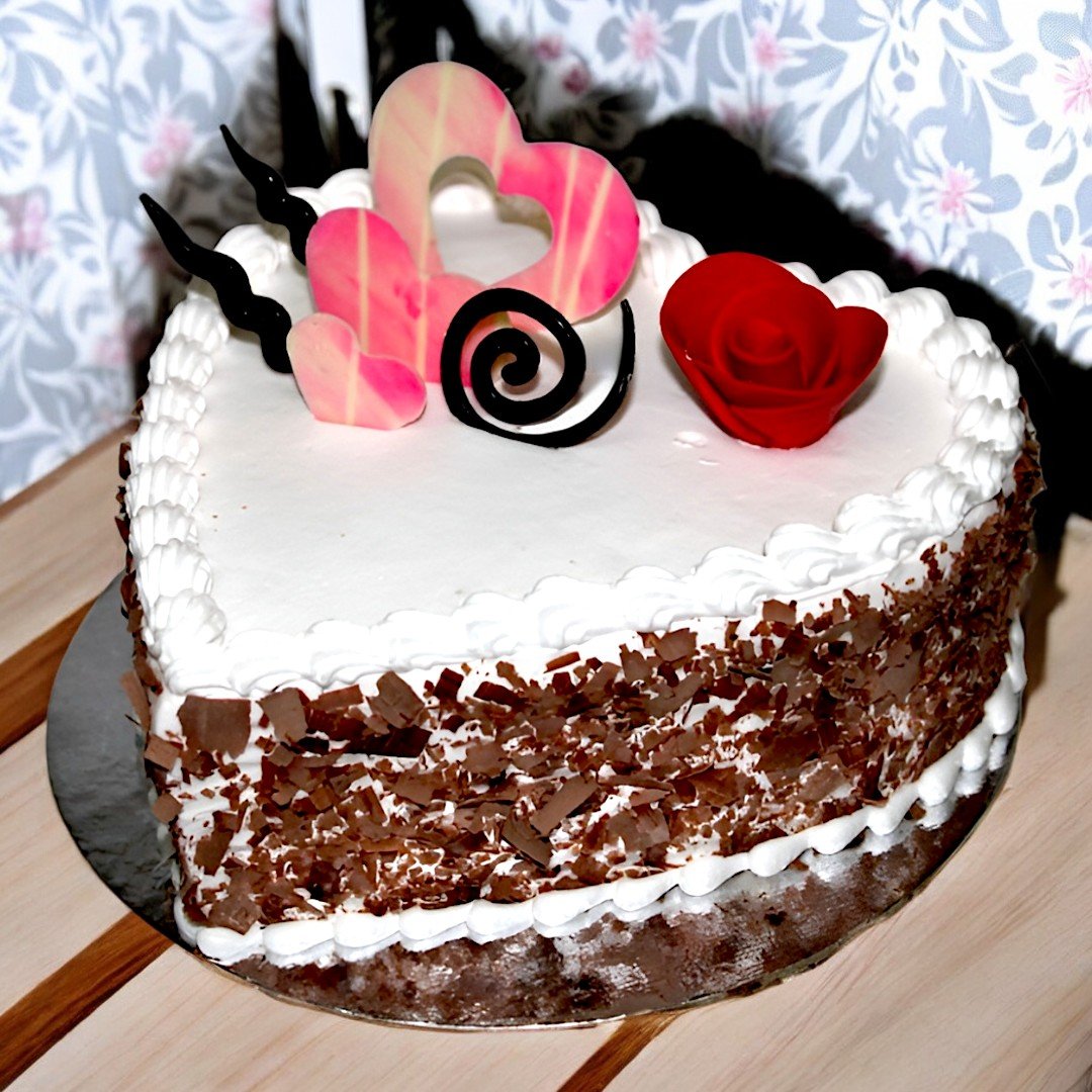 Heart Shape Black Forest Cake by BetterGiftFlowers with chocolate shavings and decorative hearts on top.