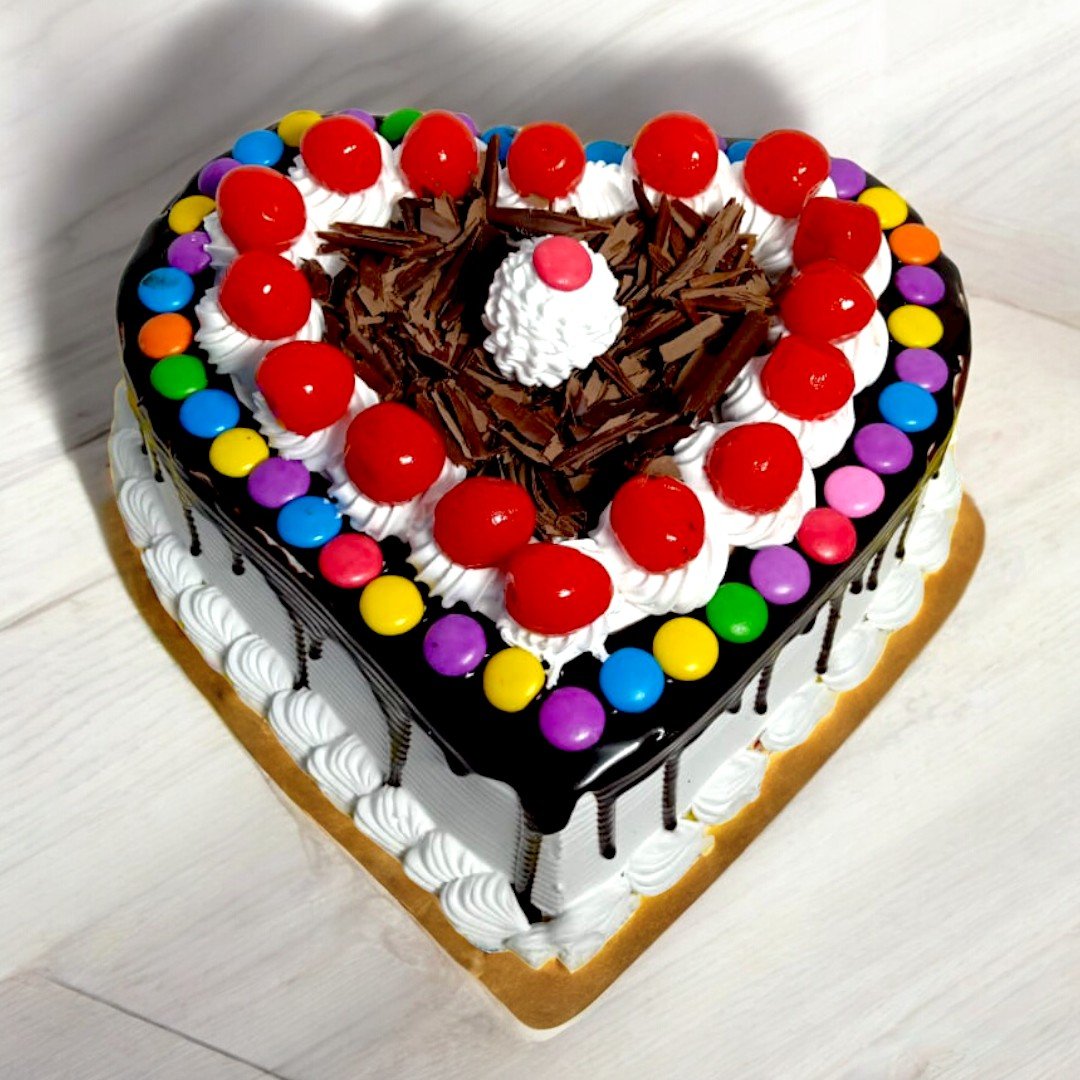 Heart Shape Black Forest Gems Cake by BetterGiftFlowers with chocolate shavings, cherries, and colorful gems topping